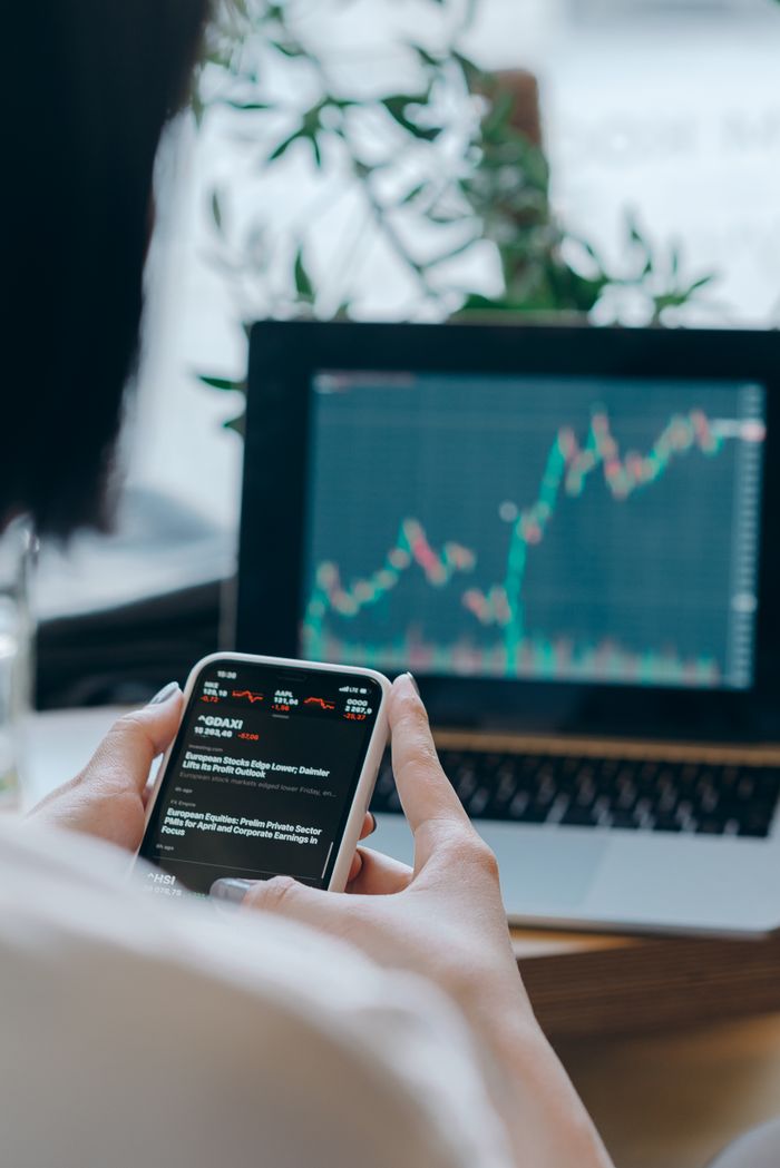 project-01-c Person using smartphone for stock market analysis at home office.